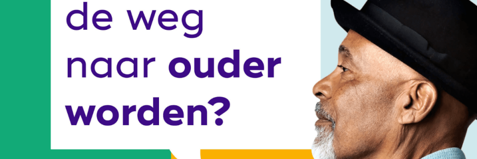 Oudere vrouw zit aan tafel met zorgmedewerker en lacht