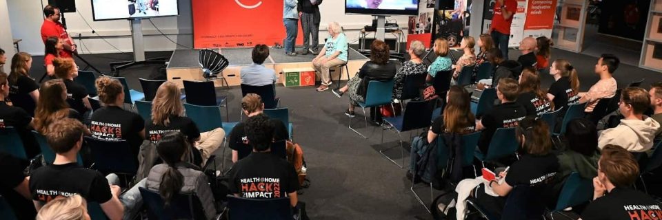 zaal vol mensen bij hack evenement