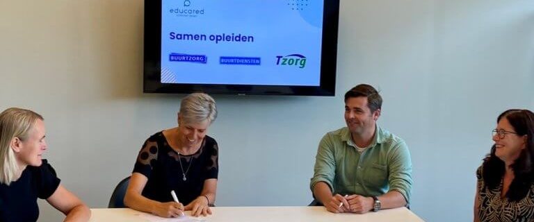 Vergadering met vier mensen en een presentatie ''samen opleiden''