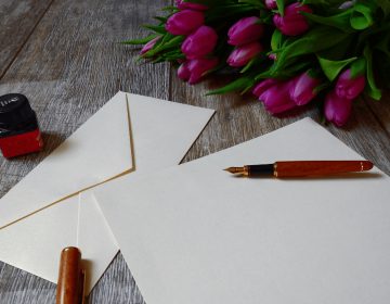 Envelop en papier met rode pen, tulpen liggen rechtsboven.