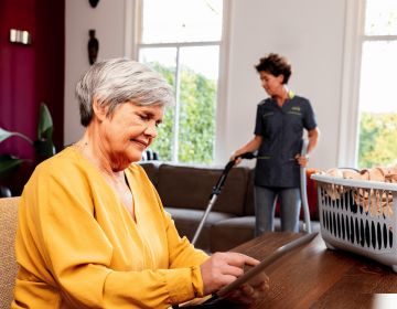 mevrouw met zorgmedewerker die stofzuigt